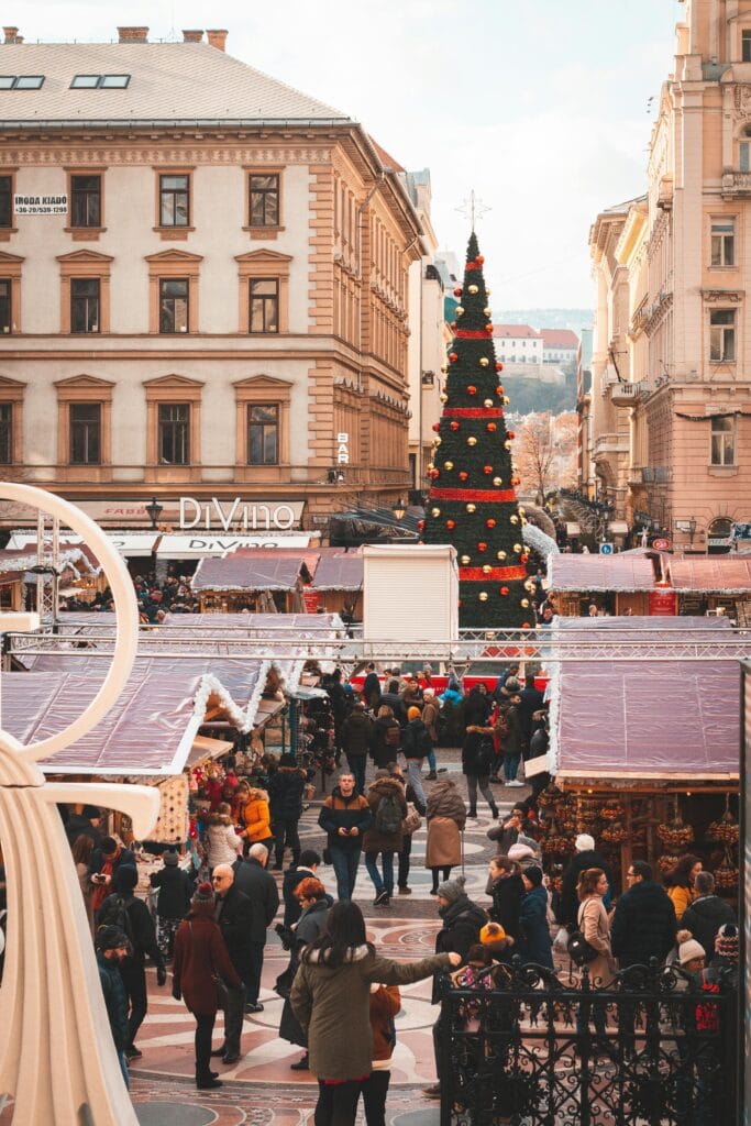 Mercado navideño de la Basílica de San Esteban en Budapest durante el invierno, con árboles decorados y puestos llenos de gente.