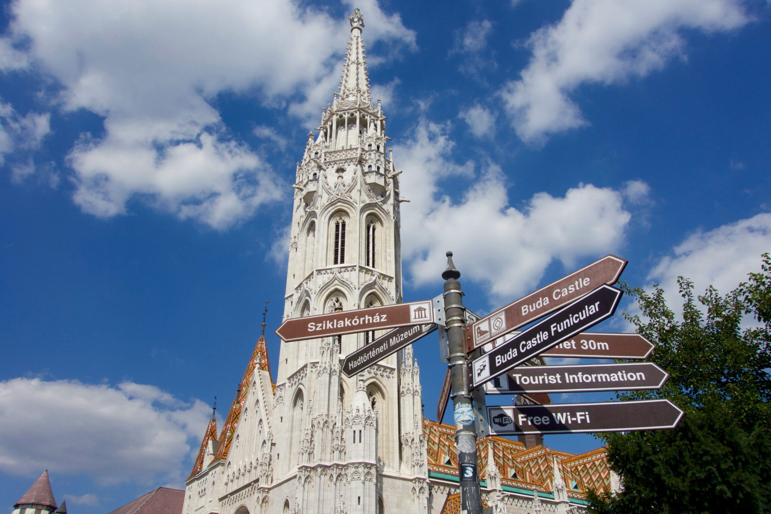 Matthias Church tower in Budapest with Buda Castle direction signs in foreground