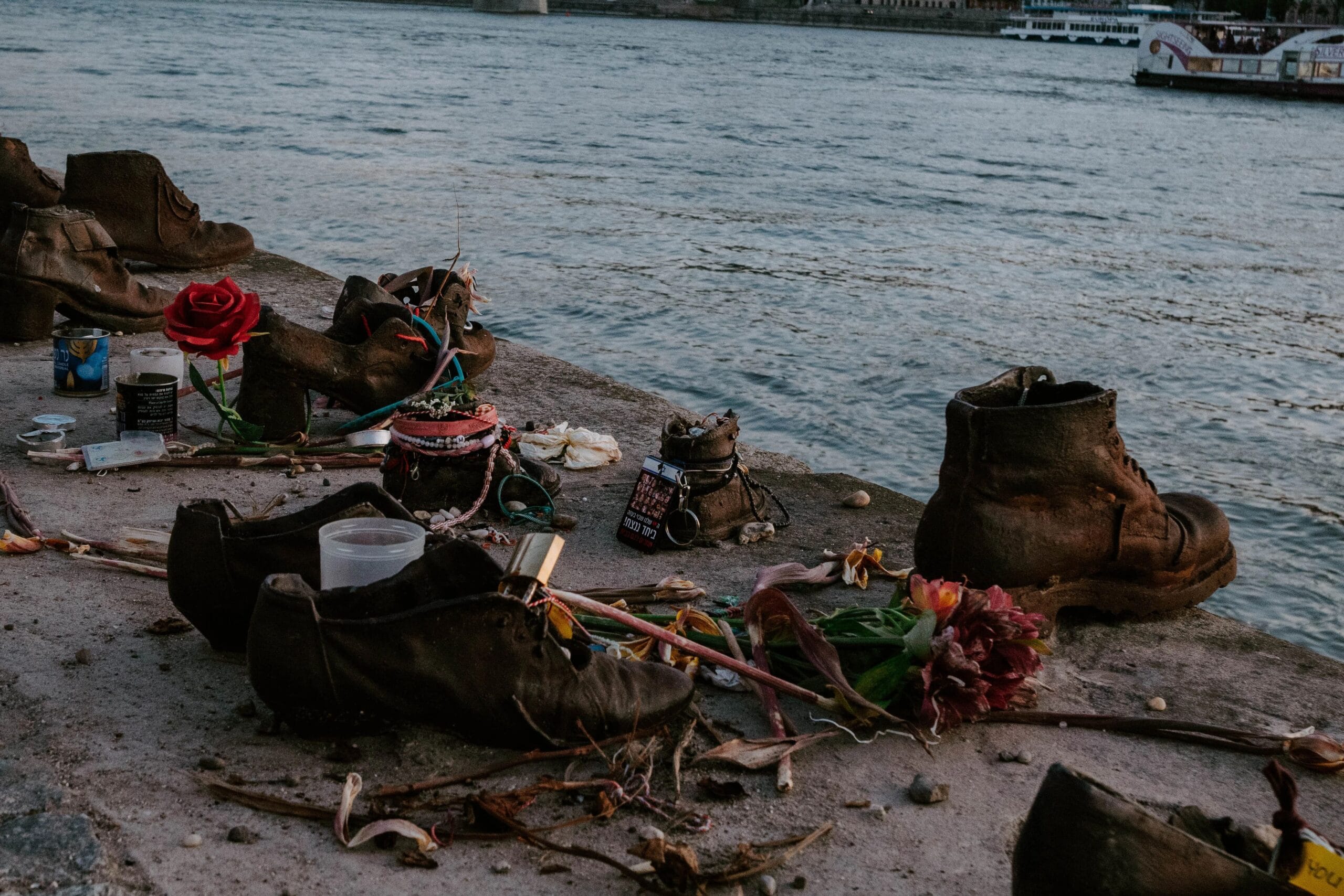 Close-up of the Shoes on the Danube memorial in Budapest with flowers and candles beside the iron shoes